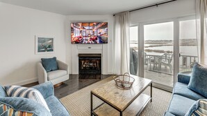 Un salon avec une cheminée, un téléviseur et une vue sur la plage.