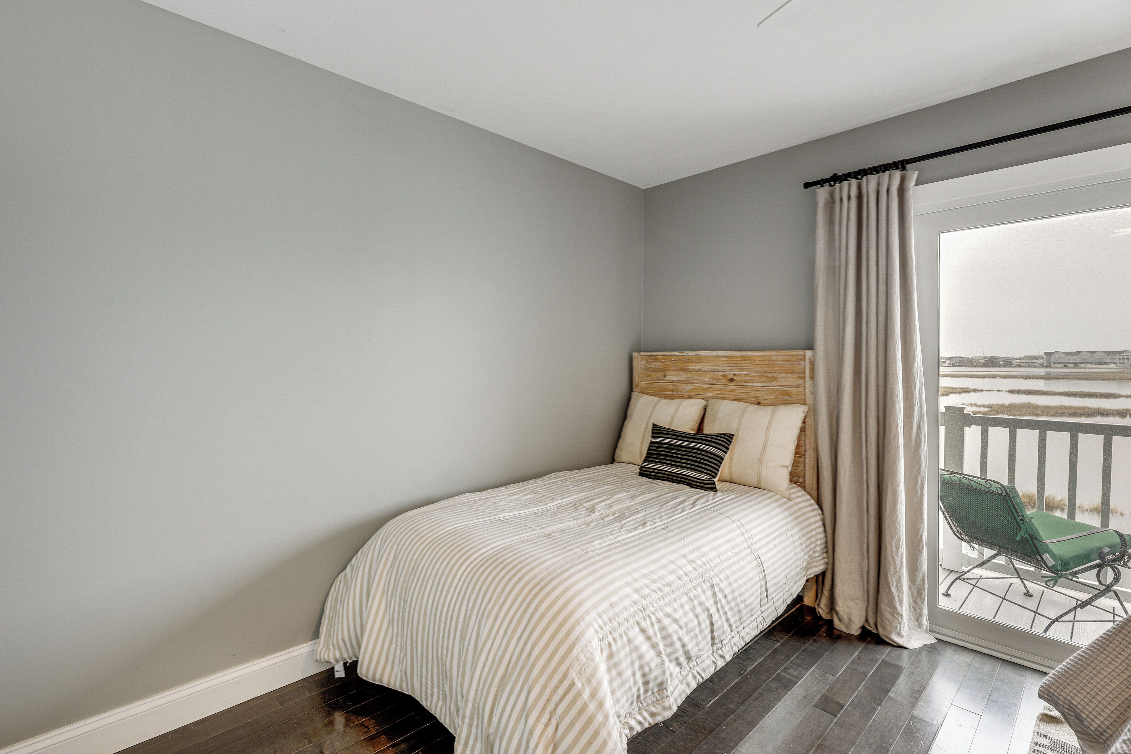 A bedroom with a bed, a window with curtains, and a view of the outside.