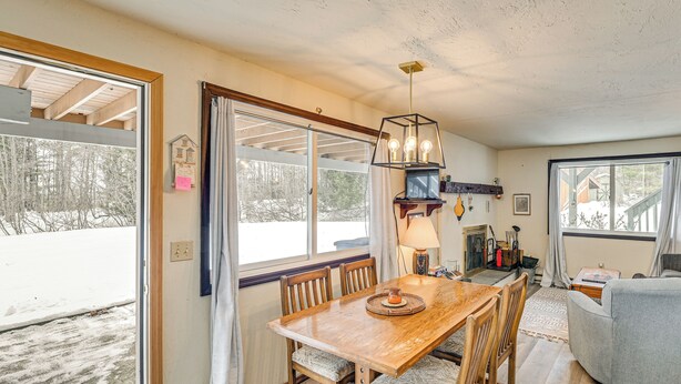 A dining area with a wooden table and chairs, a chandelier, and a view of the outdoors. - 3 Mi to Windham Mountain: Pet-friendly Apt w/ Yard (Hensonville)