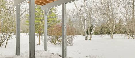 Ein mit Schnee bedeckter Außenbereich mit einer Holz-Pergola.
