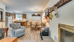 A cozy living room with a sofa, a dining table, and a fireplace. - 3 Mi to Windham Mountain: Pet-friendly Apt w/ Yard (Hensonville)
