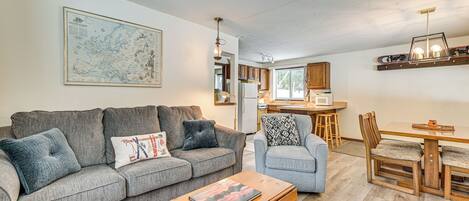 A living room with a sofa, a coffee table, and a dining area with a table and chairs.