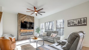 A modern living room with a fireplace, leather furniture, and large windows. - Lake Lure Getaway w/ Hot Tub & Fire Pit! (Lake Lure)