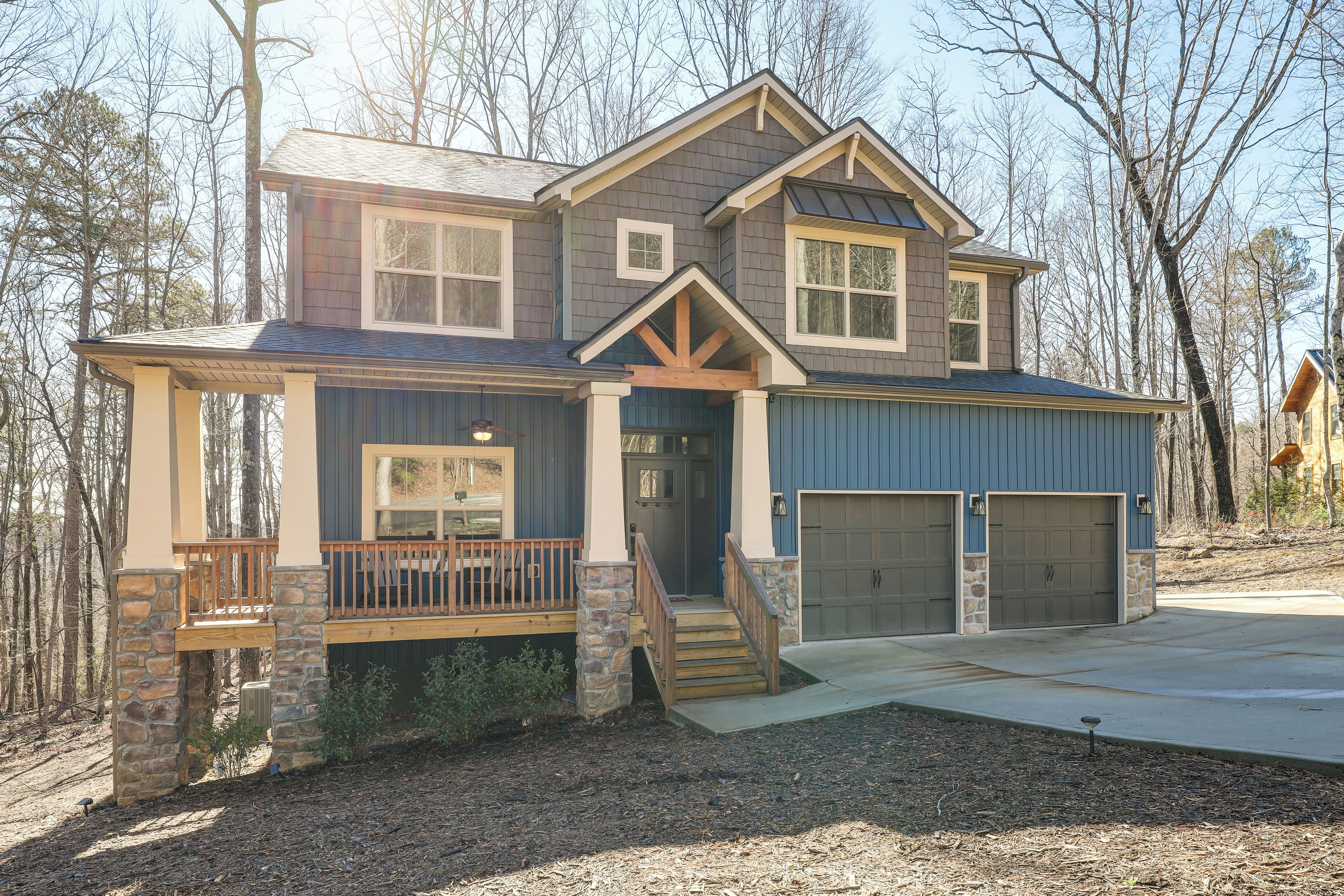 A two-story house with a stone foundation, a front porch, and a garage.
