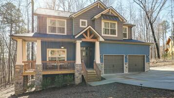 A two-story house with a stone foundation, a front porch, and a garage.