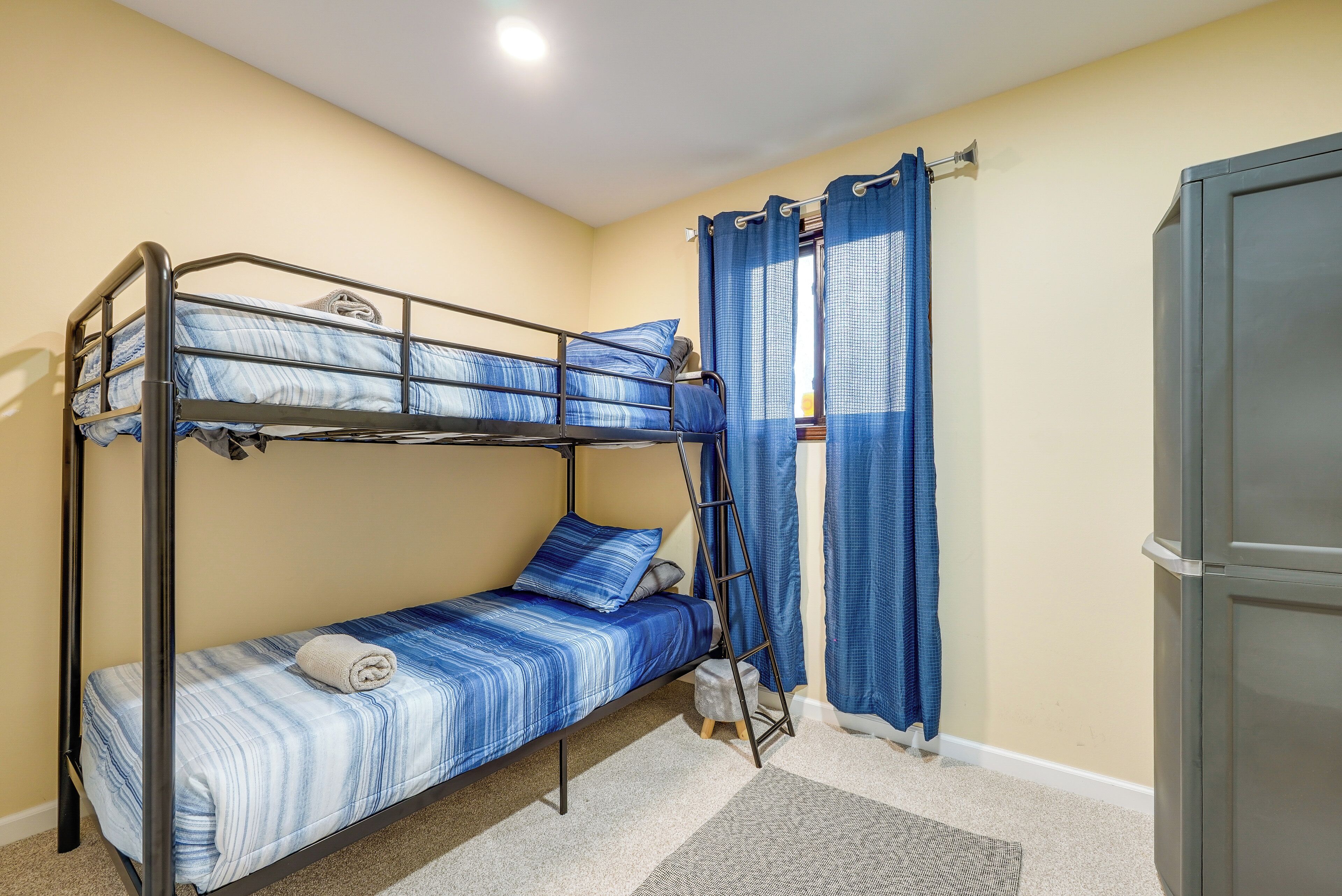 A bunk bed room with a ladder, a small stool, and a wardrobe.