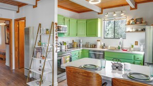 Una cocina moderna con gabinetes verdes, encimera blanca y vigas de madera en el techo.