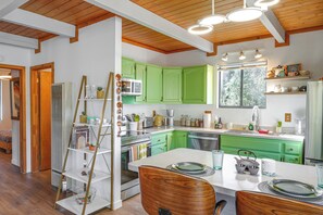 A modern kitchen with green cabinets, a white countertop, and wooden ceiling beams. - Access to Pool & Trails: Pine Mountain Club Cabin (Pine Mountain Club)