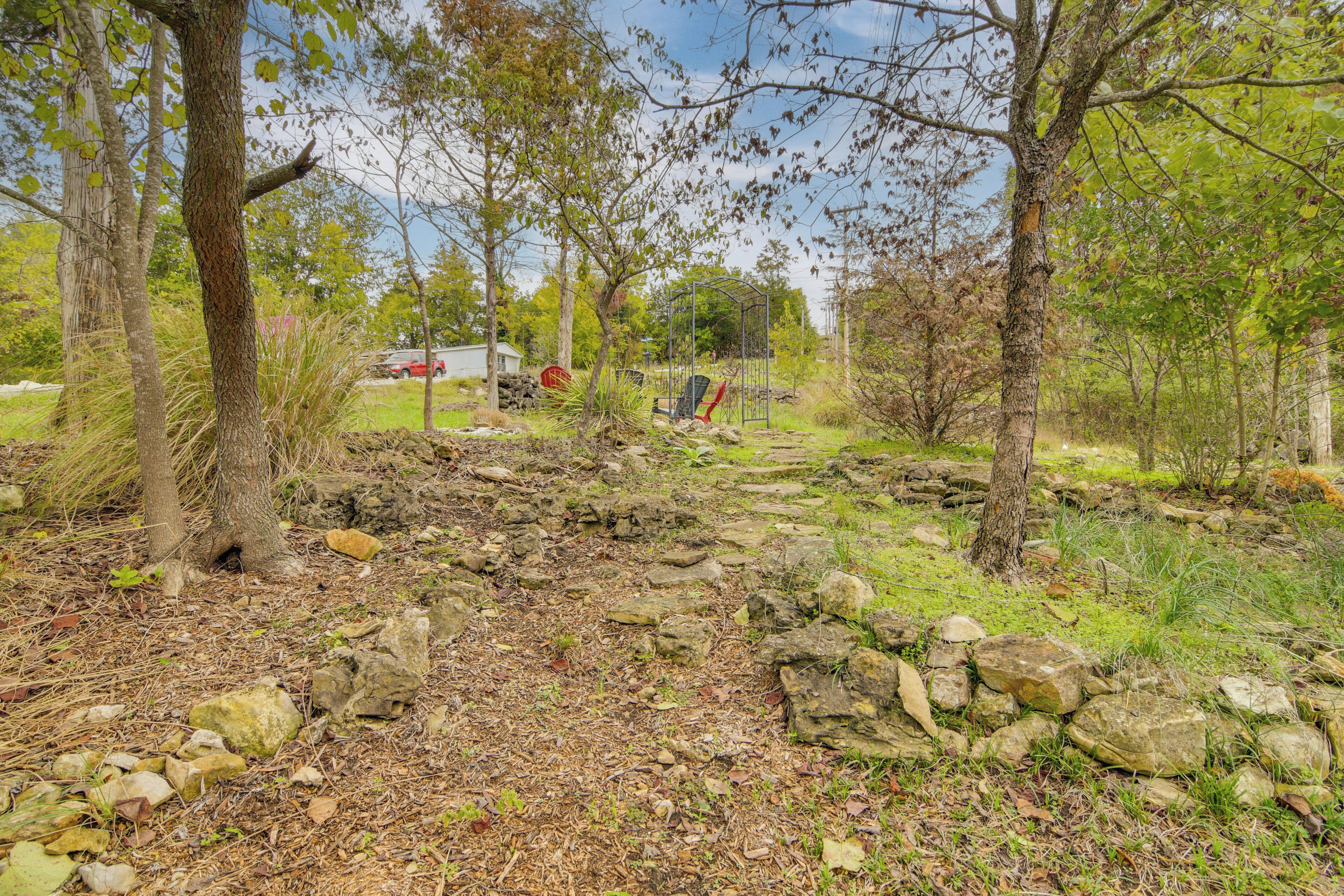A natural outdoor area with a stone pathway, trees, and a metal structure.