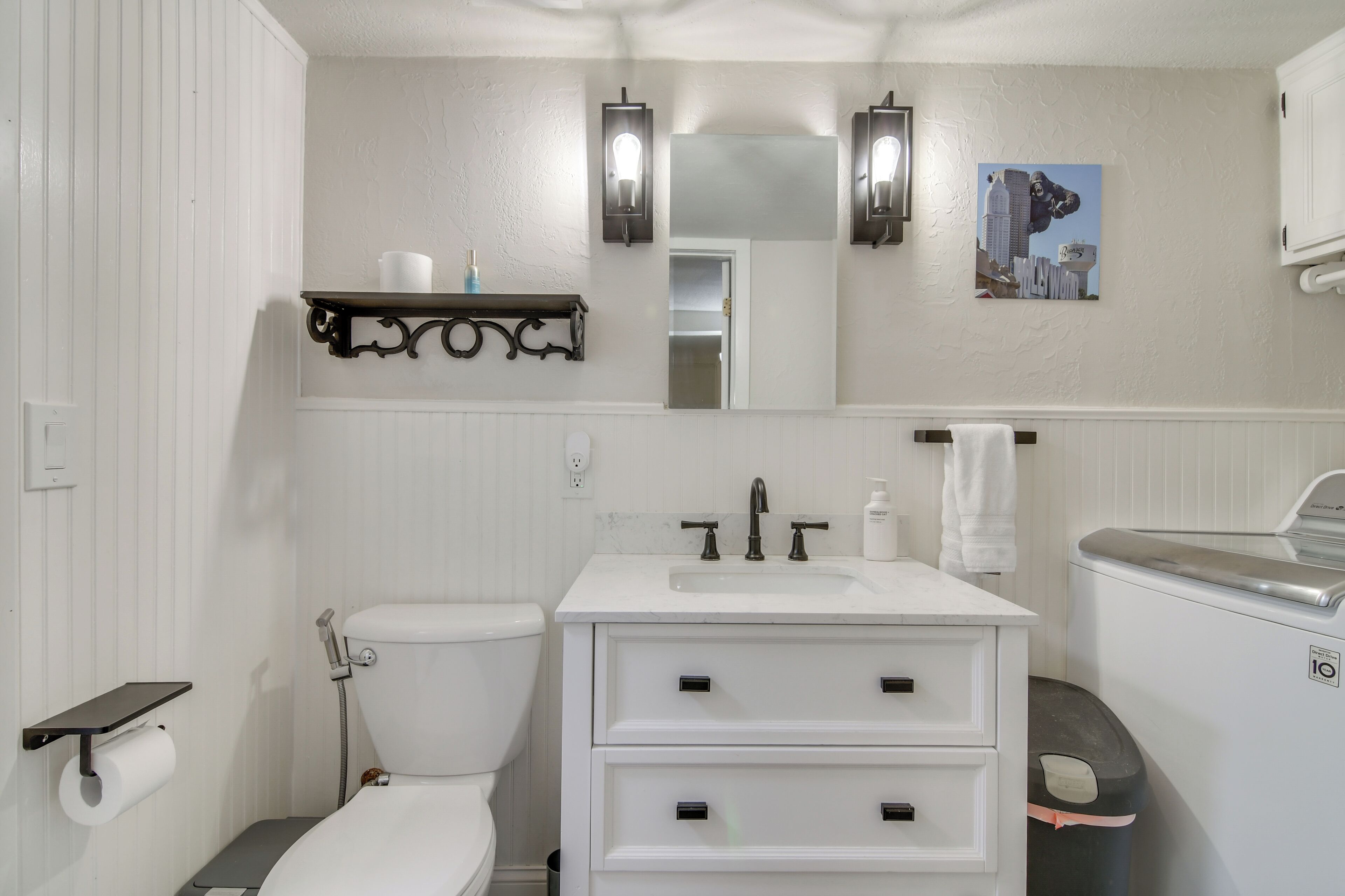 A bathroom with a toilet, sink, vanity, and a mirror.