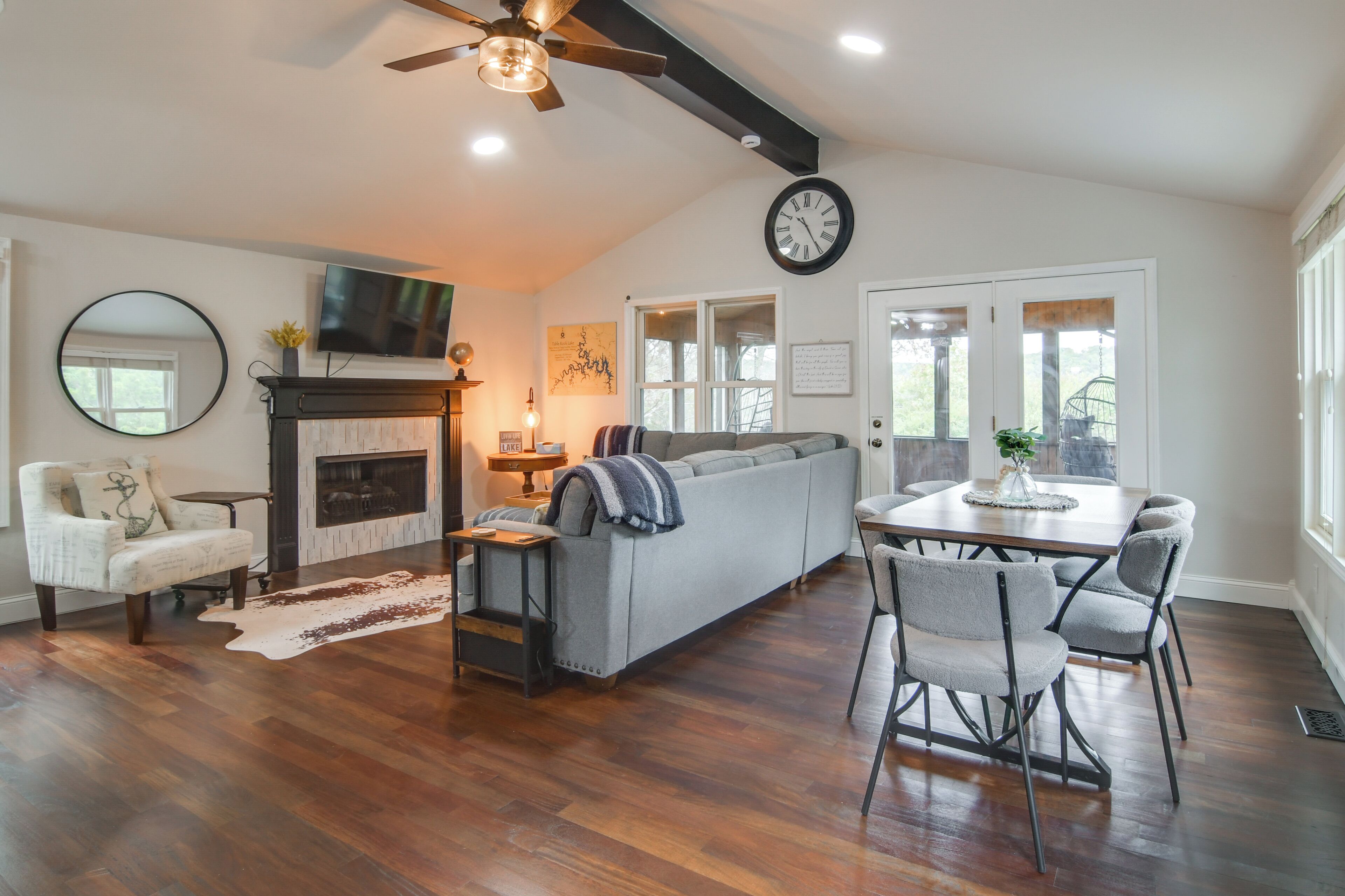 A spacious living room with a fireplace, a sofa, a dining table with chairs, and a ceiling fan.