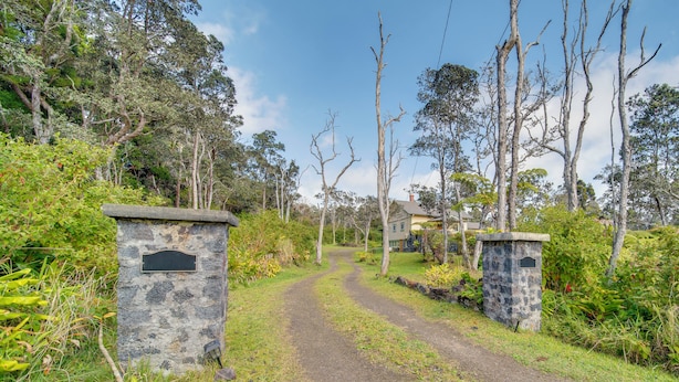 A rural pathway leading to a house surrounded by trees and vegetation. - Lush Island Oasis Near Volcanoes National Park (Volcano)