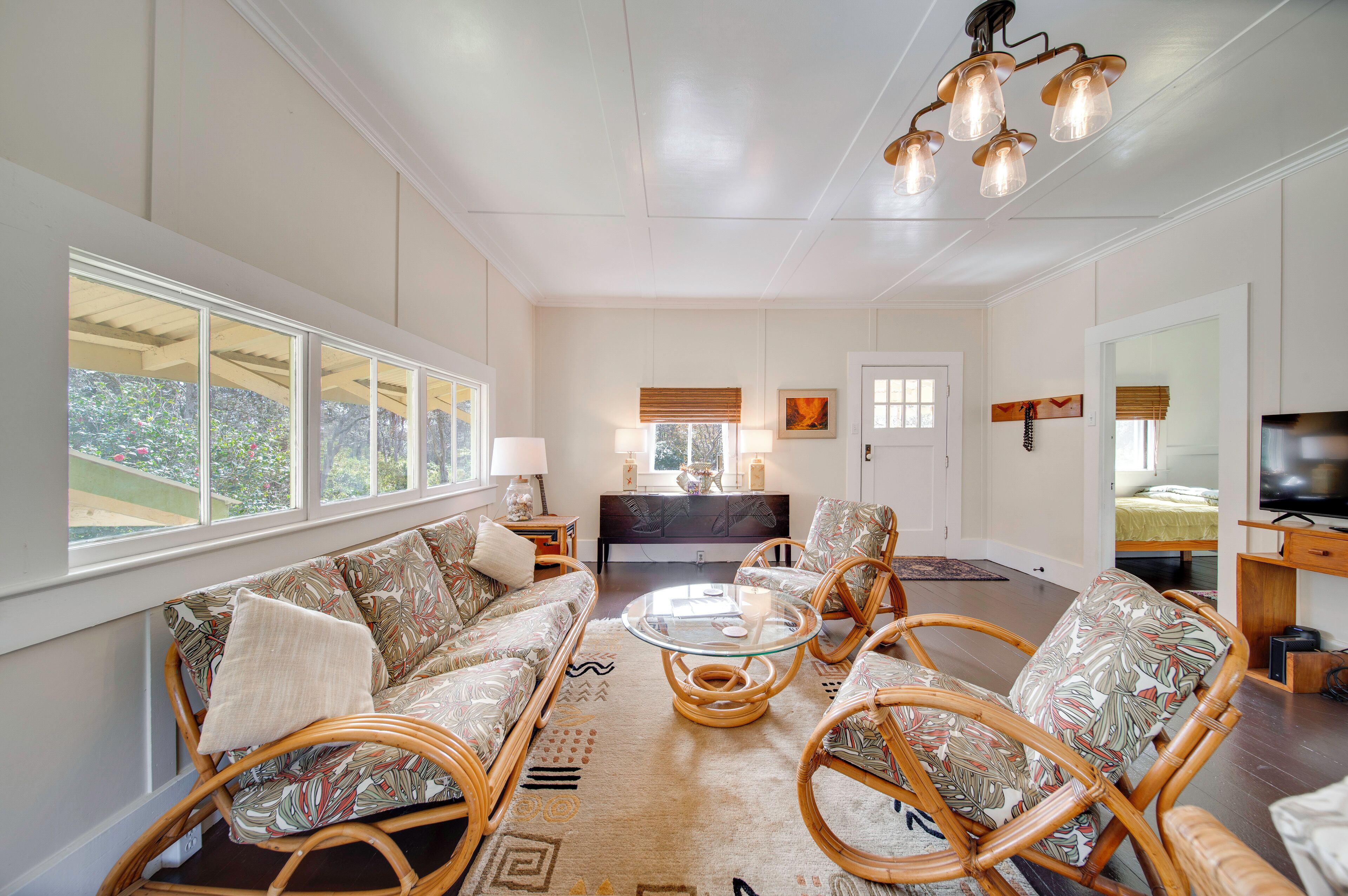 A spacious living room with a sofa, chairs, a glass coffee table, and a TV.
