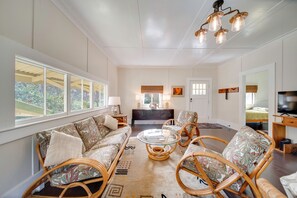 A spacious living room with a sofa, chairs, a glass coffee table, and a TV. - Lush Island Oasis Near Volcanoes National Park (Volcano)