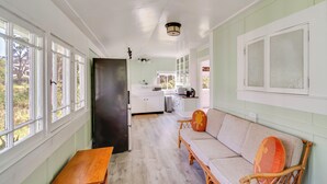 A hallway with a wooden bench, a black door, and a kitchen area with white cabinets and a sink. - Lush Island Oasis Near Volcanoes National Park (Volcano)