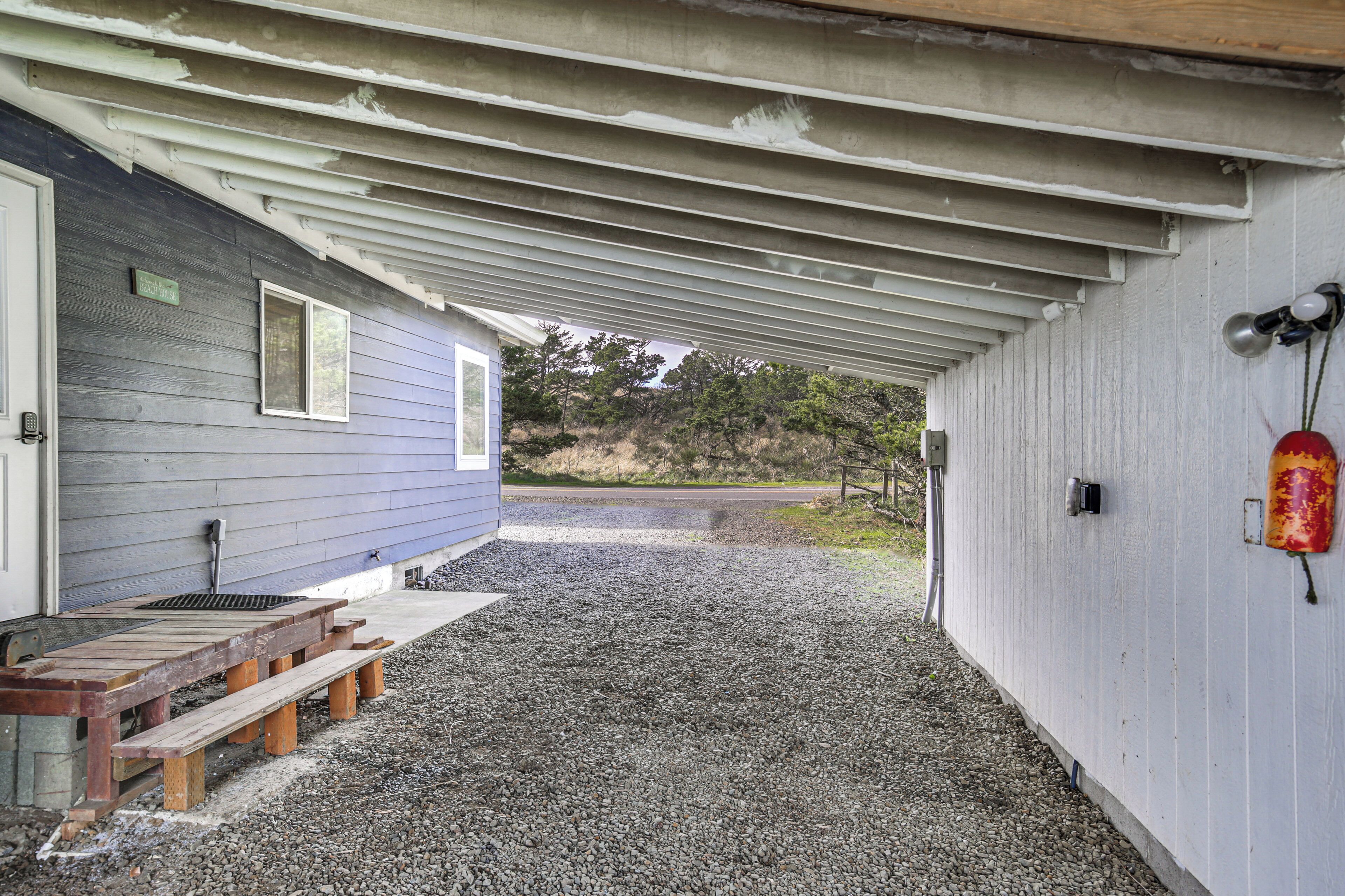 A covered outdoor area with a gravel path leading to a building with a window and a bench.