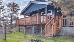 Une maison à deux étages avec une terrasse en bois et un mur en pierre.