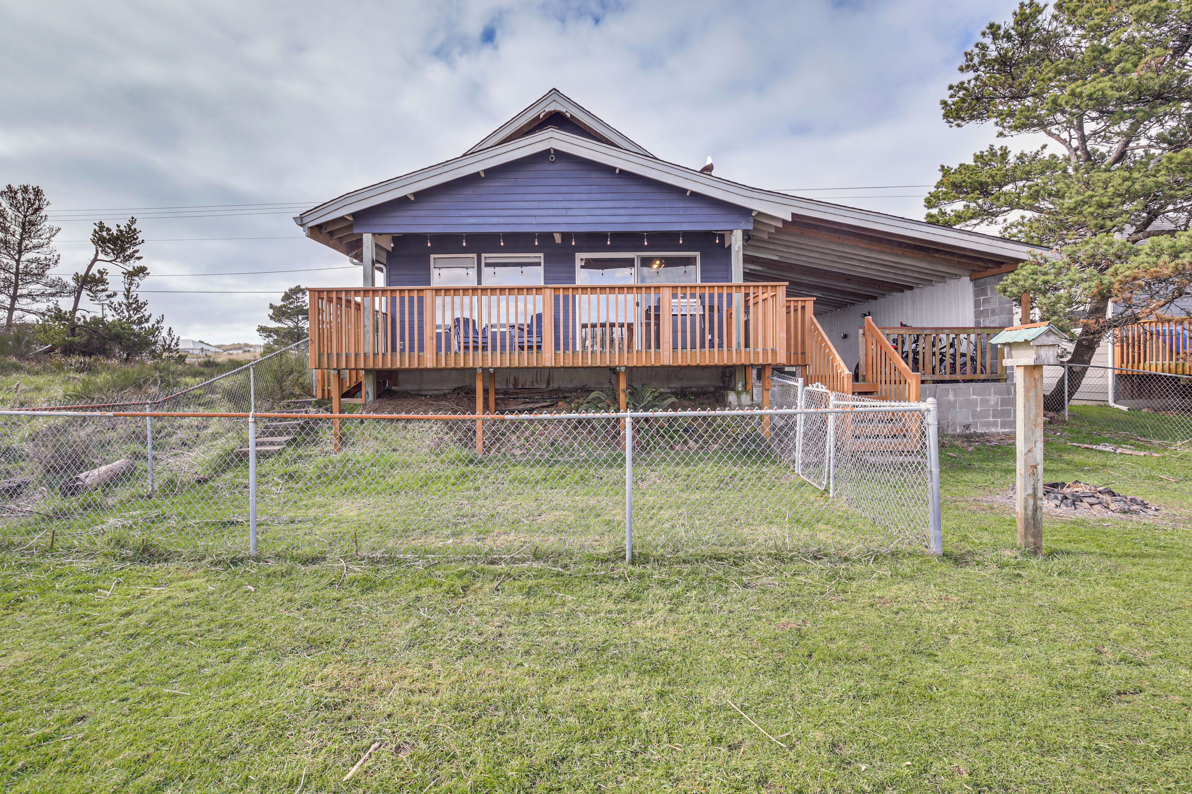 Une maison à deux étages avec une terrasse en bois et une cour clôturée.