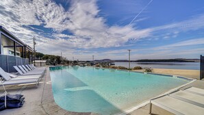 A swimming pool with lounge chairs and a view of a beach and mountains. - Pool Access, Walk to Water! Possum Kingdom Cabin (Graford)