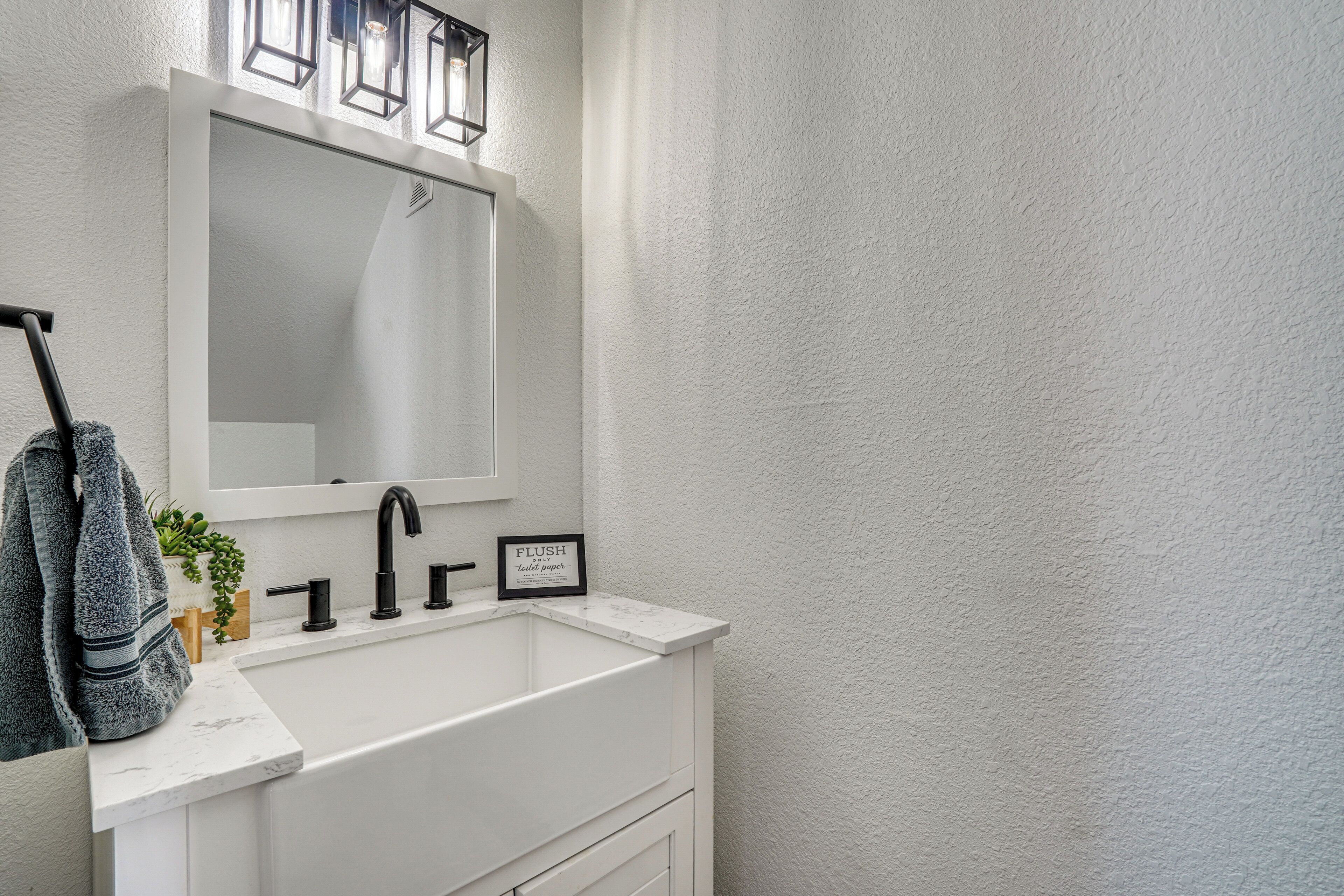 Une salle de bain avec un lavabo blanc, un robinet noir et un miroir au-dessus.