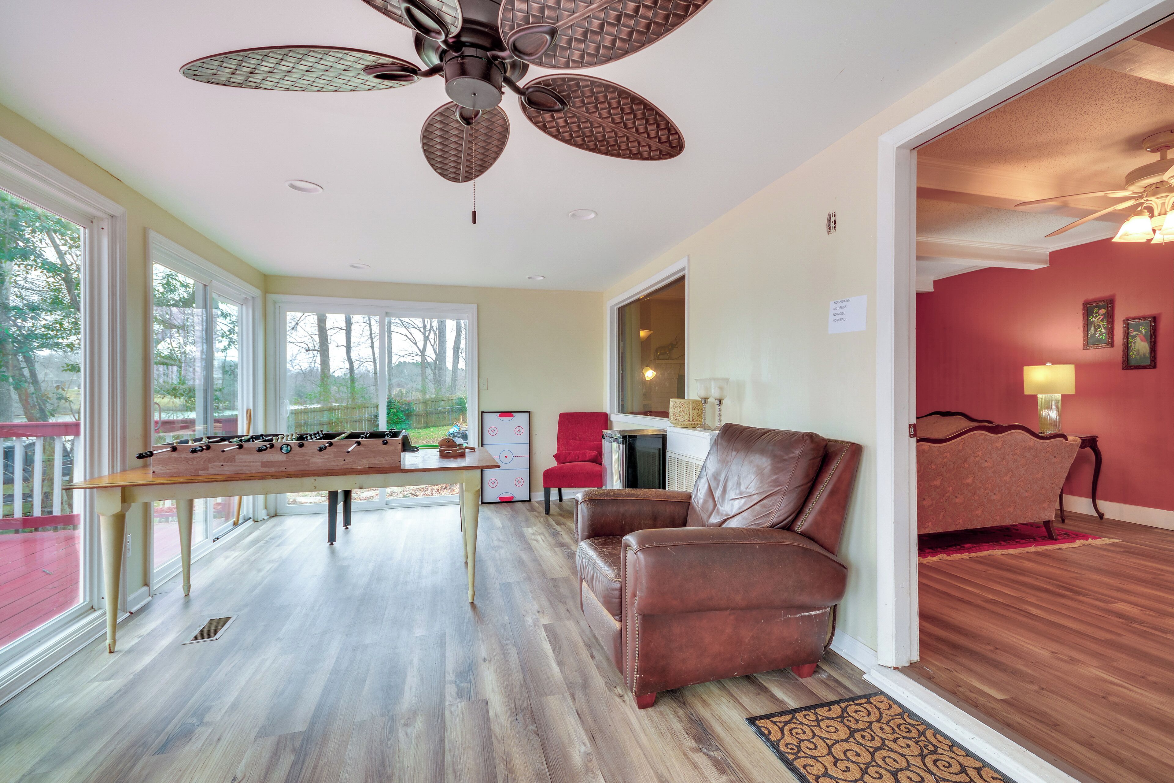 Una habitación amplia con mesa de fútbol, sofá de cuero y ventilador de techo.