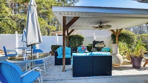 An outdoor patio with a covered seating area, a table, and chairs.