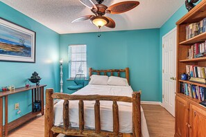 A bedroom with a wooden bed, a ceiling fan, a bookshelf, and a painting on the wall. - Hot Tub + Gazebo: Group Getaway Near Dtwn Conway! (Conway)
