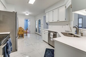 Una cocina moderna con armarios blancos, un refrigerador de acero inoxidable y un lavavajillas integrado.