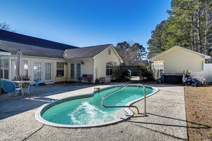 Un patio trasero residencial con piscina, un porche cubierto y un cobertizo pequeño.