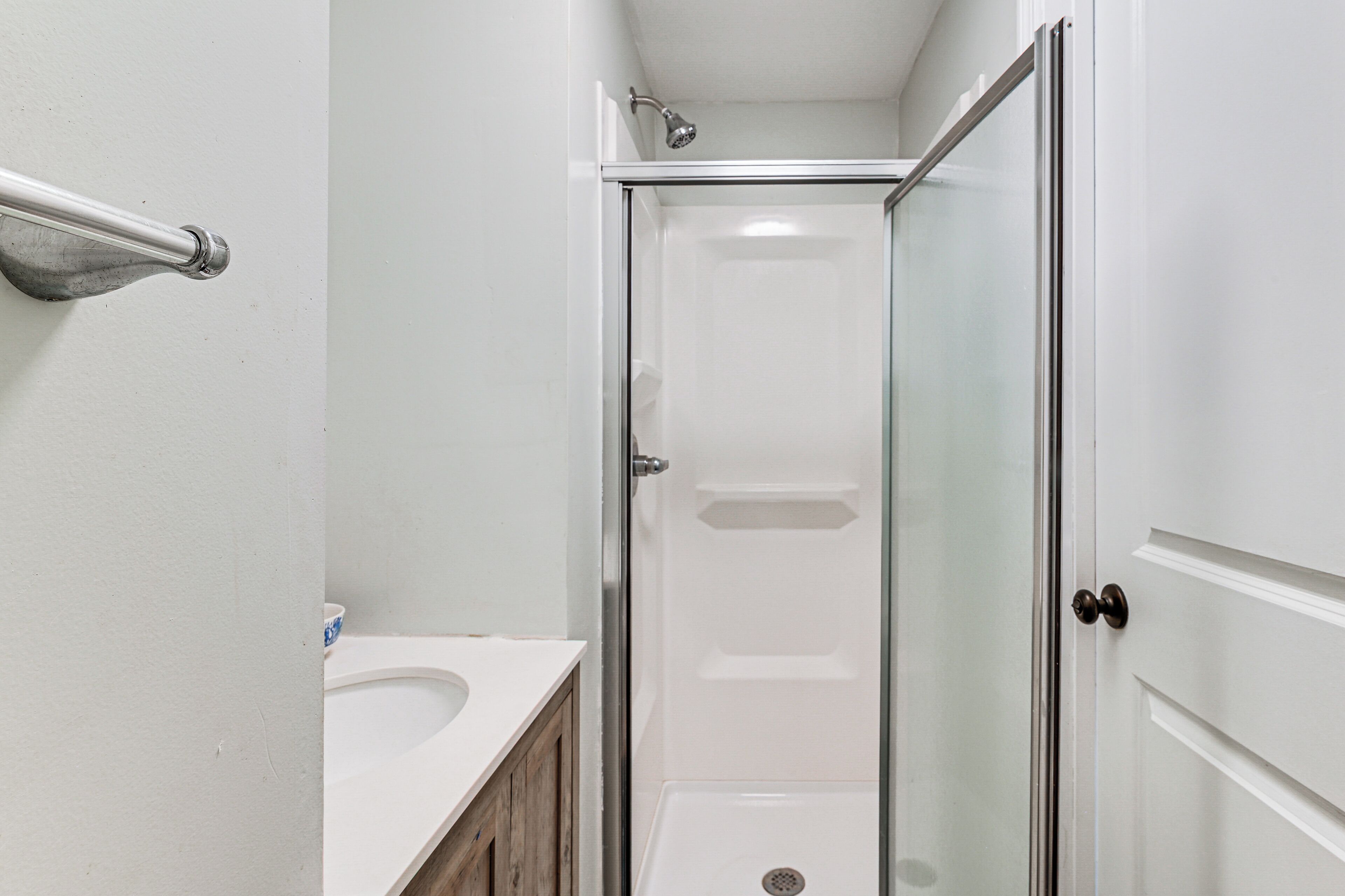 A bathroom with a shower, a sink, and a door.