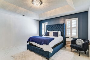 Een slaapkamer met een groot bed, een nachtkastje, een stoel en een kroonluchter.