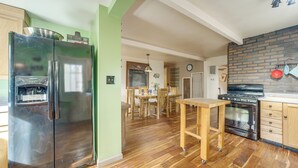 A kitchen with a stainless steel refrigerator, wooden dining table, and a brick backsplash. - Great for Families! Woodsy Haven in Happy Jack (Happy Jack)