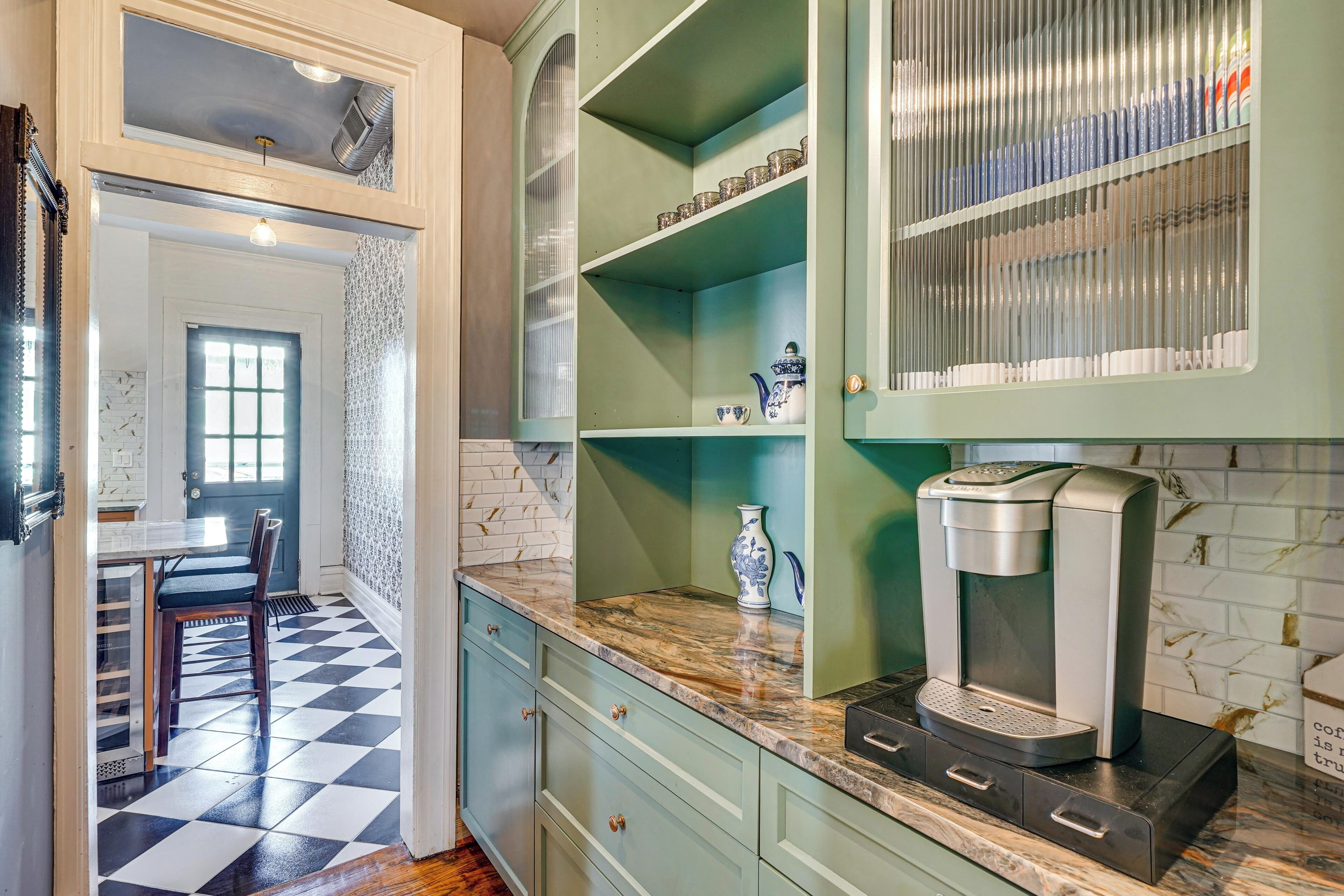 A kitchen with a checkered floor, a coffee maker on the counter, and a window with a view.
