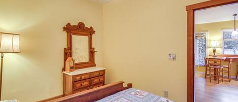 A bedroom with a wooden bed, a dresser, a mirror, and a lamp.