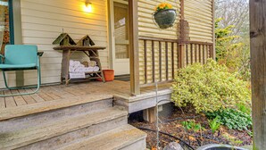 A wooden porch with steps leading to a door, a hanging flower pot, and a small table with towels and a basket. - Walk to Irondale Beach Park! Family Haven w/ Yard (Port Hadlock)