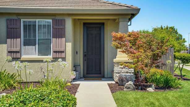 A residential house with a front door, a window with shutters, a small porch area, and a garden with various plants and a tree. - Sophisticated Sanctuary: 8 Mi to Lodi Wineries! (Stockton)