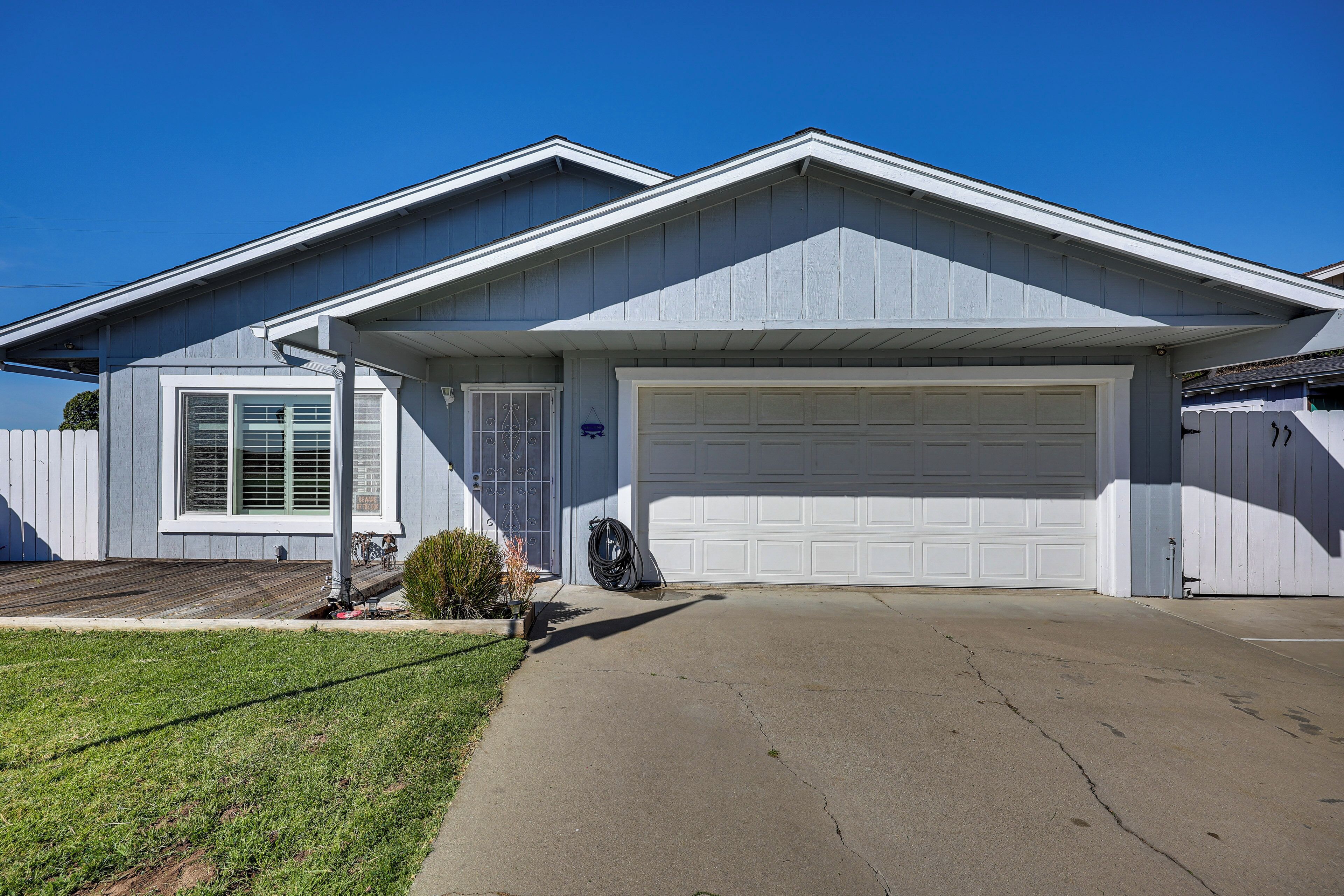 A residential house with a garage, a front yard, and a clear blue sky.