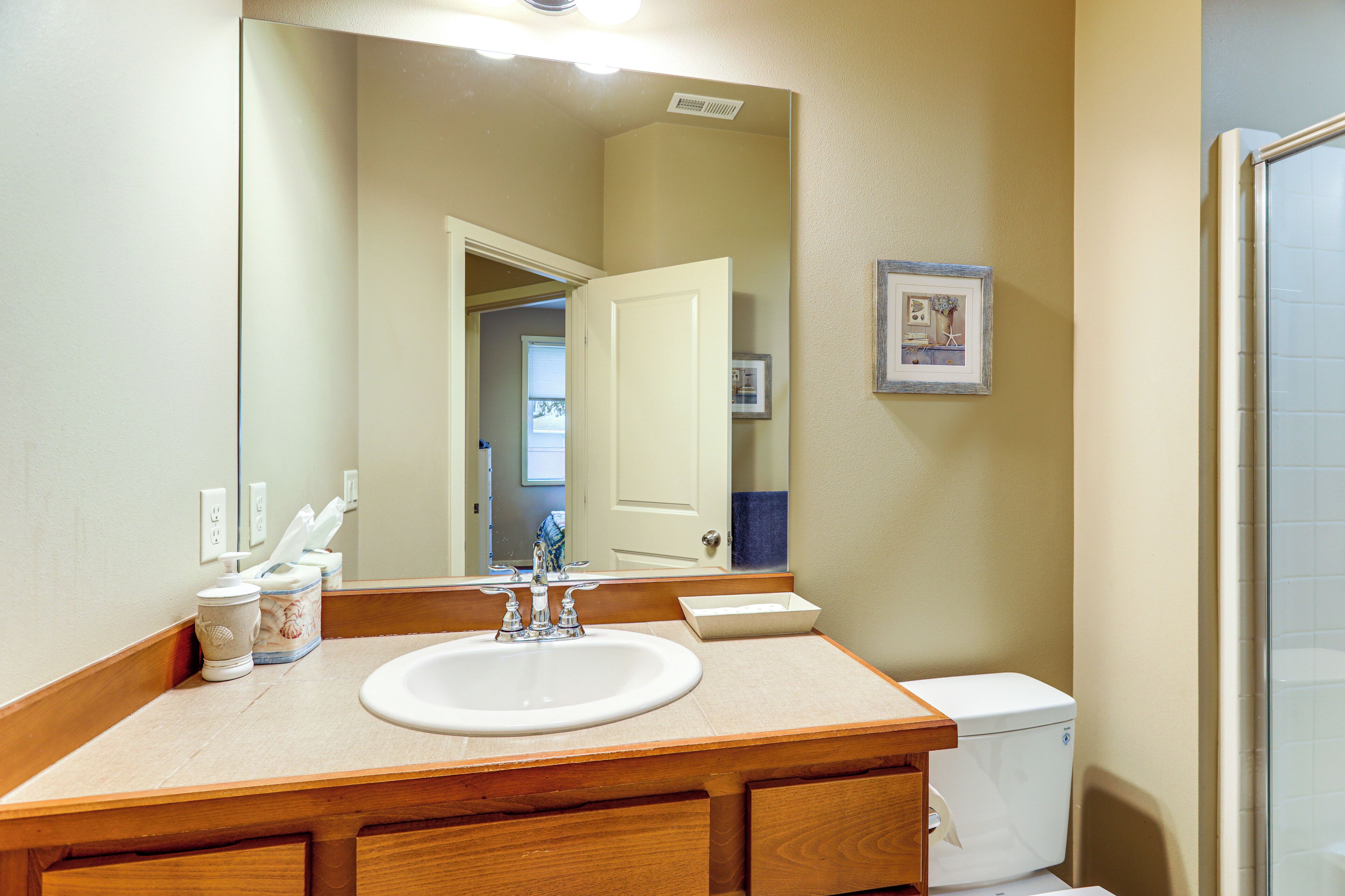 A bathroom with a wooden vanity, white sink, and a large mirror.