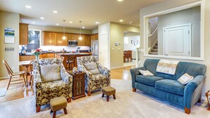 A spacious living area with a blue sofa, patterned armchairs, and a wooden dining table. - Gateway to Greater Seattle! Spacious, Modern Home (Bothell)