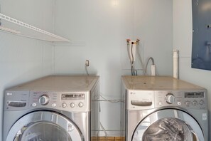 Two stacked front-loading washing machines in a laundry room with a white shelf above and a blue wall with a power outlet. - 4 Mi to Siesta Beach: Sarasota Gem w/ Movie Room! (Sarasota)