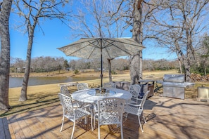 A deck with a round table and chairs, a grill, and a view of a lake. - Hot Tub + Deck: Waterfront Lake Limestone Escape! (Jewett)