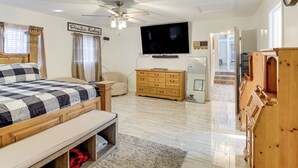 A bedroom with a bed, a wooden dresser, a television, and a ceiling fan. - Meech Legacy House Southern Charm & Cozy Comfort (Benton)