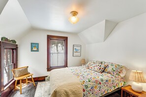 Une chambre à coucher avec un lit, une chaise, une fenêtre et une lampe.