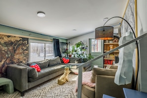 A living room with a sofa, a coffee table, a dog, a staircase, and a bookshelf. - < 1 Mi to Dtwn Brandon! Cozy Home w/ Fenced Yard (Brandon)