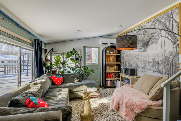 A cozy living room with a sofa, a coffee table, a bookshelf, and a large window. - < 1 Mi to Dtwn Brandon! Cozy Home w/ Fenced Yard (Brandon)