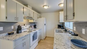 A modern kitchen with white cabinets, a built-in oven, a refrigerator, and a granite countertop. - Dog-friendly Townhome Near Stillaguamish River! (Arlington)