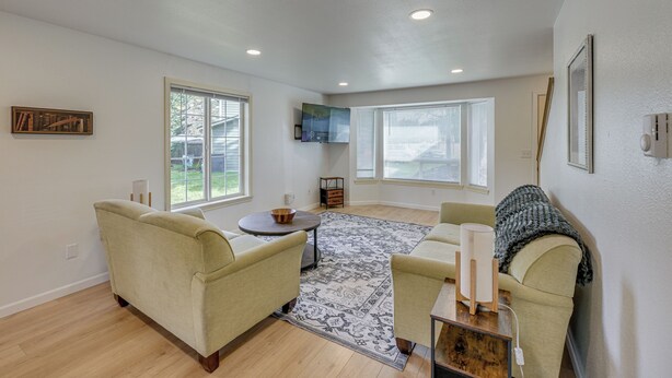 A spacious living room with a large window, a fireplace, and a cozy seating area. - Dog-friendly Townhome Near Stillaguamish River! (Arlington)