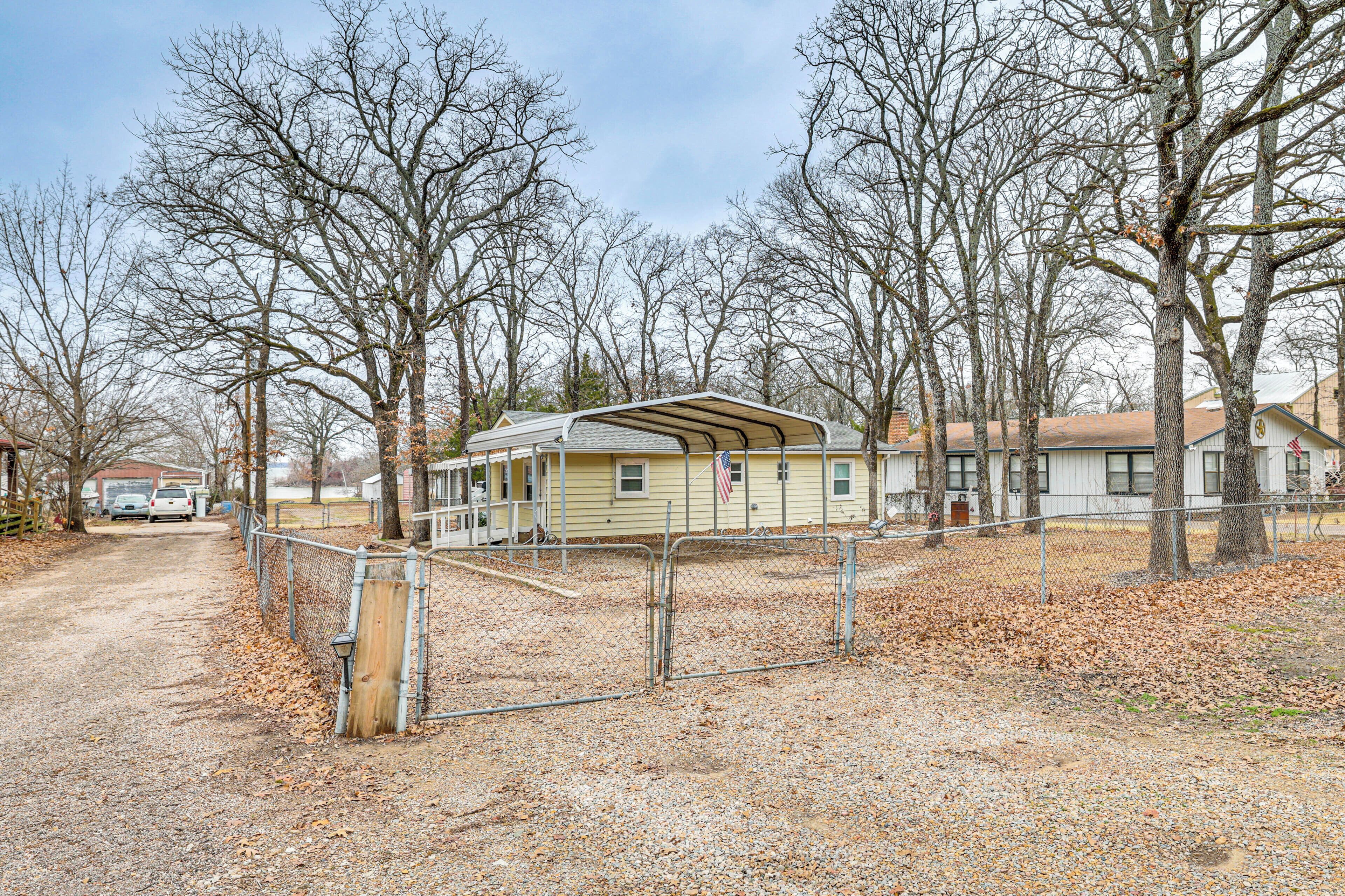 A single-story building with a covered porch, surrounded by trees and a gravel driveway.