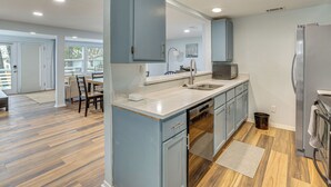 A modern kitchen with blue cabinets, a stainless steel refrigerator, and a dishwasher.