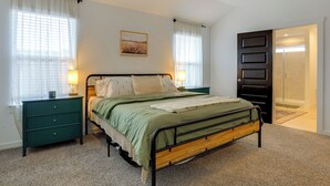 A bedroom with a bed, nightstands, a dresser, and a door leading to a bathroom. - Resort Perks & Private Yard: Brookshire Retreat (Katy)